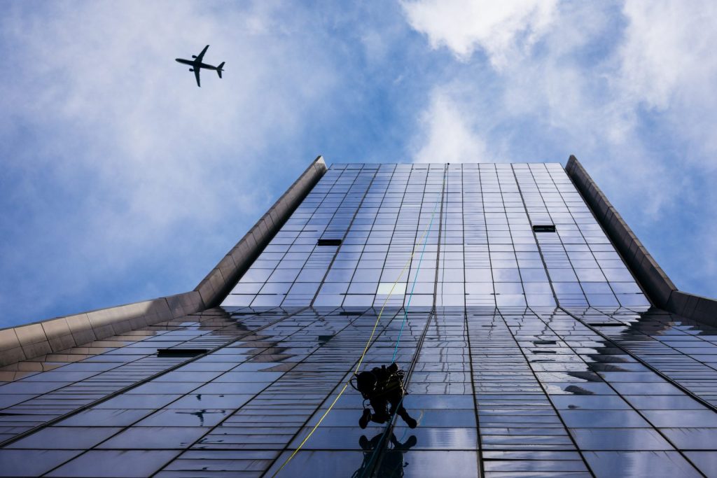 Técnico de trabajos verticales sobre la fachada acristalada de un edificio