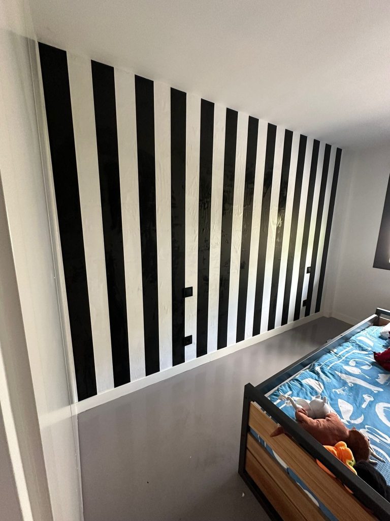 Dormitorio reformado con pared de rayas en blanco y negro