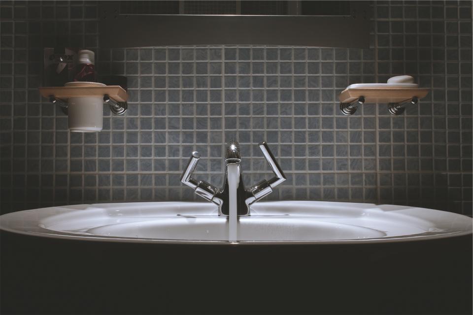 Baño reformado con lavabo de diseño y paredes alicatadas en gris oscuro