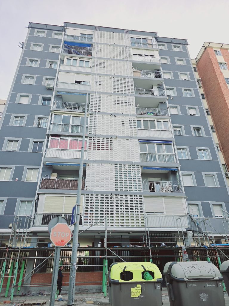 Fachada rehabilitada en tonos gris y blanco con andamio en la planta baja