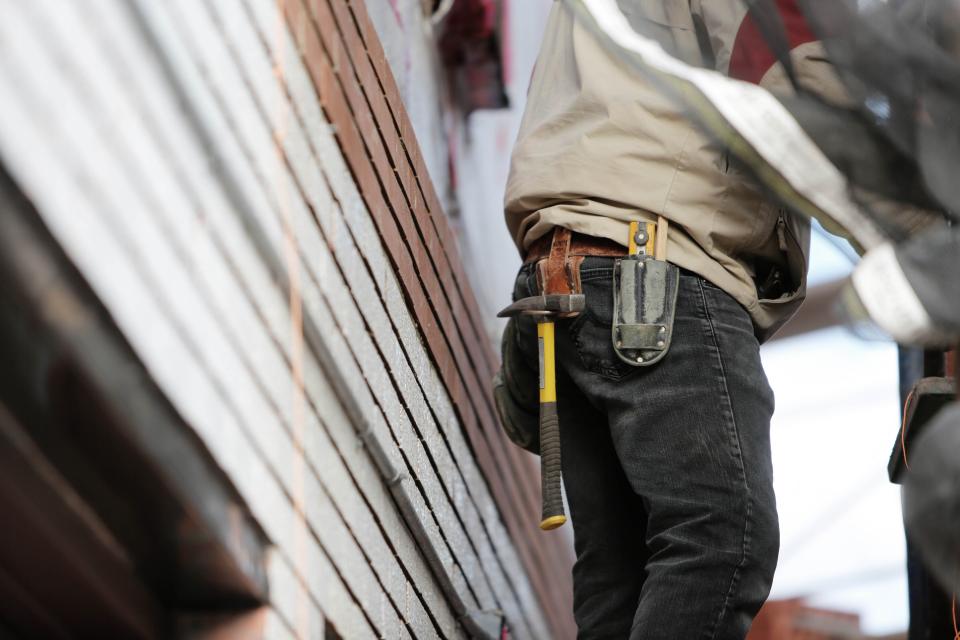 Operario con cinturón de herramientas trabajando en una obra